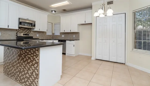 a kitchen with kitchen island granite countertop a sink cabinets and stainless steel appliances
