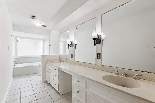 a spacious bathroom with a granite countertop sink a toilet a mirror and bathtub