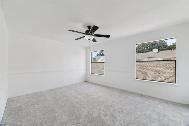 an empty room with a window and a ceiling fan