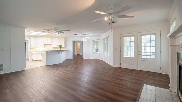 an empty room with wooden floor fireplace and windows