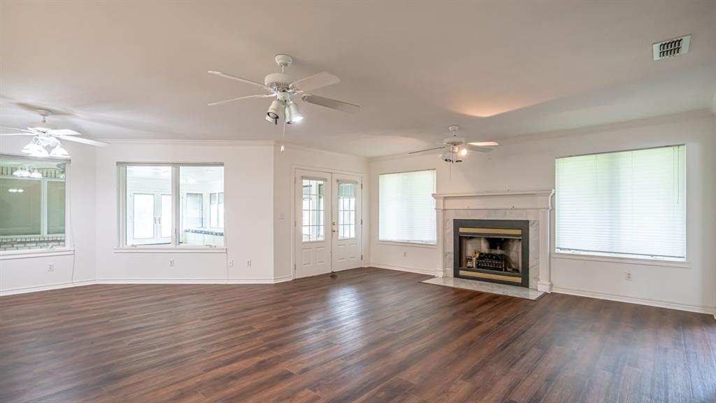 111 Scenic Drive Dublin, TX 76446 - Photo 12 of 40 an empty room with wooden floor fireplace and windows
