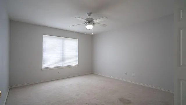 an empty room with a window and a fan