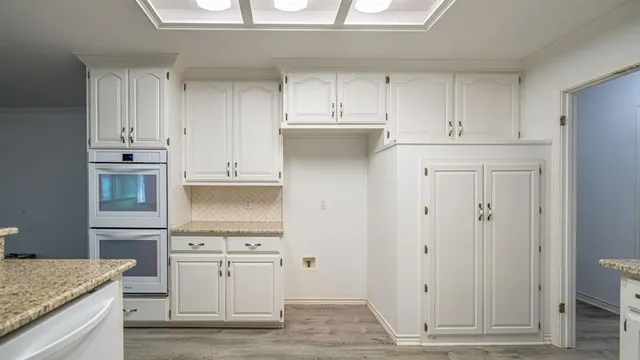 an empty room with wooden floor and kitchen