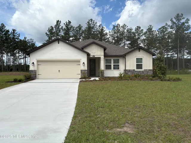 a front view of house with yard and trees in the background