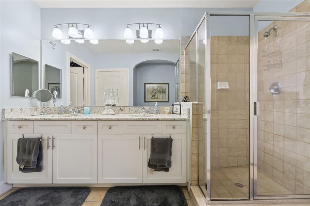 515 Mirasol Circle, Unit 302 Celebration, FL 34747 - Photo 35 of 60 a bathroom with a granite countertop sink a mirror and shower view