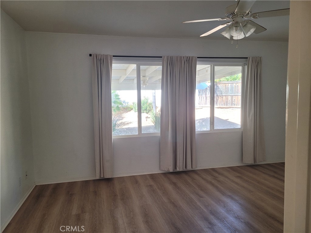 25540 Turfwood Street Menifee, CA 92585 - Photo 26 of 27 an empty room with wooden floor chandelier fan and windows