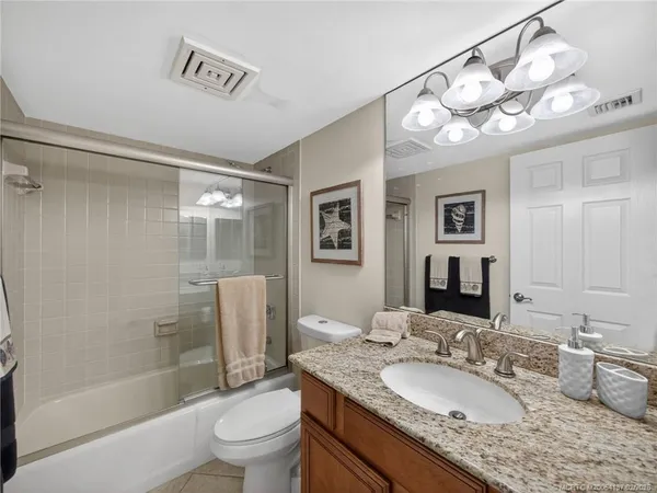 a bathroom with a granite countertop sink toilet mirror and shower