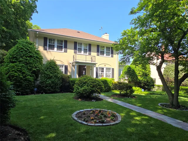 a view of a white house with a big yard and potted plants and trees