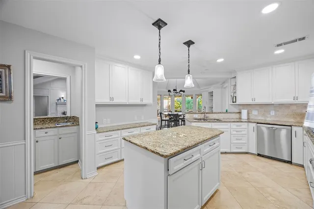 a kitchen with a stove a sink a center island a counter top space and cabinets