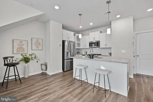 a kitchen with stainless steel appliances granite countertop a refrigerator a oven a sink a stove and white cabinets with wooden floor