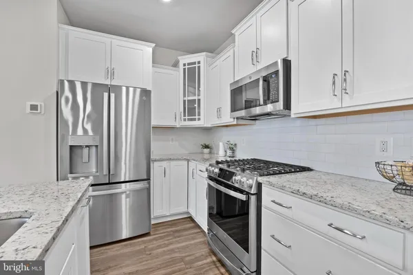 a kitchen with granite countertop white cabinets and stainless steel appliances