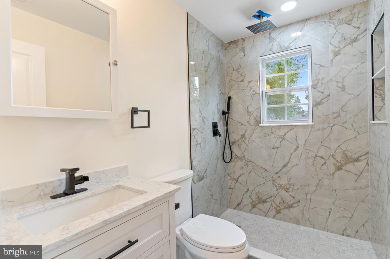 7315 Marlboro Pike District Heights, MD 20747 - Photo 13 of 32 a bathroom with a granite countertop sink a toilet and shower