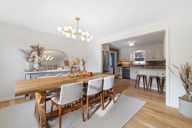 a dining area with furniture a chandelier and kitchen view