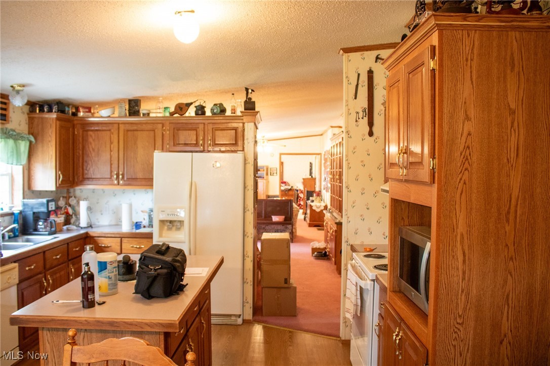 61691 Wintergreen Road Lore City, OH 43755 - Photo 29 of 50 Kitchen with white appliances, light wood-style flooring, light countertops, brown cabinets, and a textured ceiling