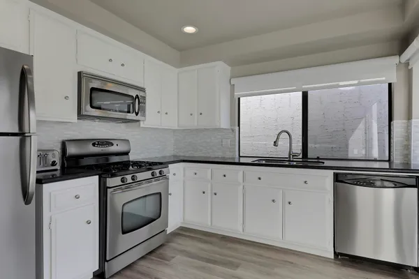 a kitchen with granite countertop white cabinets white stainless steel appliances and sink