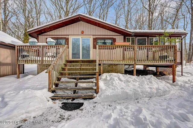 a view of a house with wooden deck and furniture