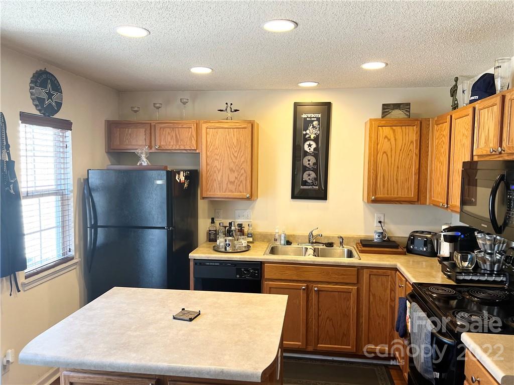 11222 Grass Field Road Charlotte, NC 28213 - Photo 5 of 12 a kitchen with a refrigerator a stove a sink dishwasher and wooden cabinets