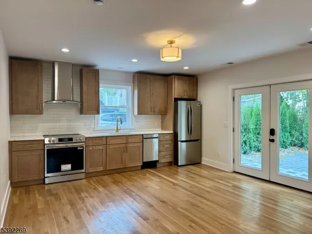 a large kitchen with a refrigerator a sink dishwasher a stove and a dining table with wooden floor