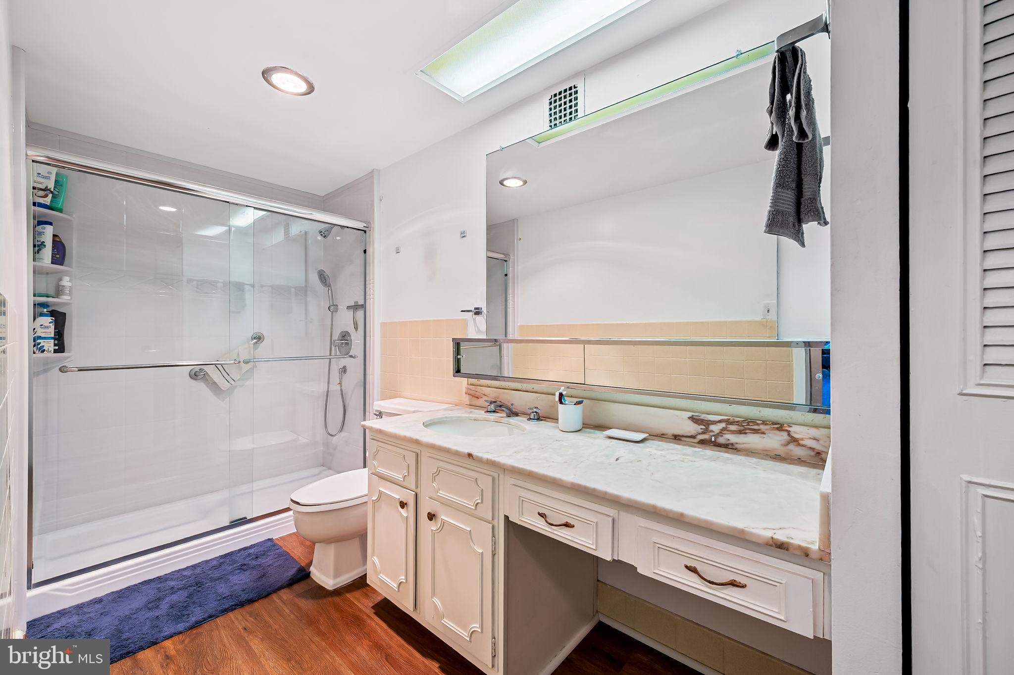 4401 Roland Avenue, Unit 110 Baltimore, MD 21210 - Photo 19 of 23 a bathroom with a granite countertop sink a toilet and shower