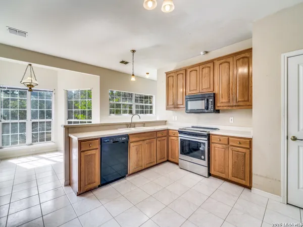 a large kitchen with stainless steel appliances granite countertop a stove sink and cabinets