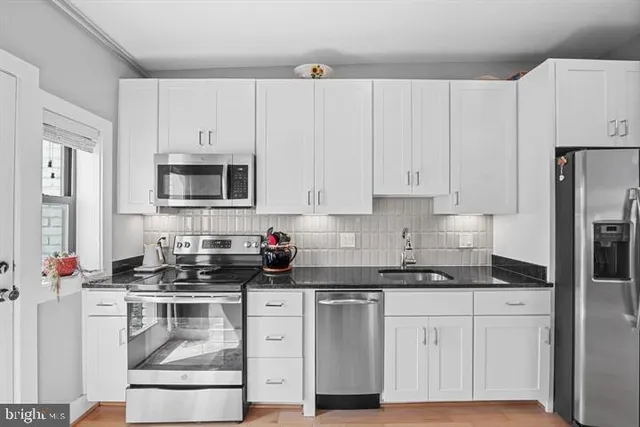 a kitchen with granite countertop white cabinets and stainless steel appliances