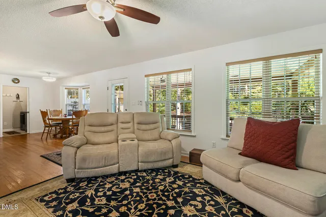 a kitchen with stainless steel appliances granite countertop a stove top oven a sink dishwasher a dining table and chairs with wooden floor