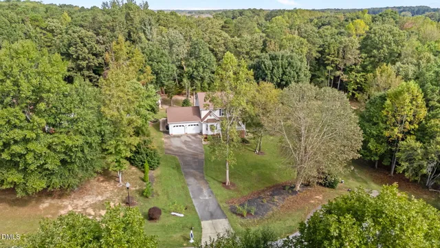 an aerial view of residential house with outdoor space and trees all around