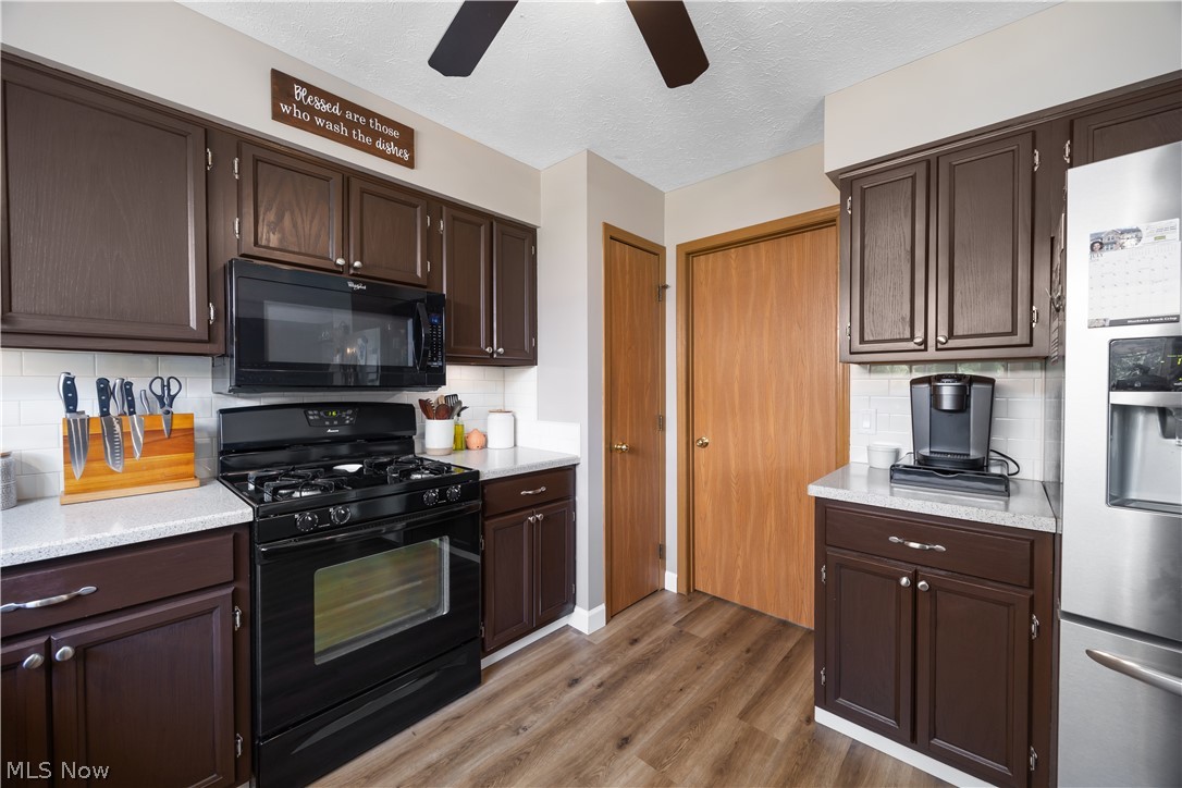 684 Guilford Road Vermilion, OH 44089 - Photo 15 of 37 Kitchen with black appliances, wood-type flooring, tasteful backsplash, ceiling fan, and dark brown cabinetry