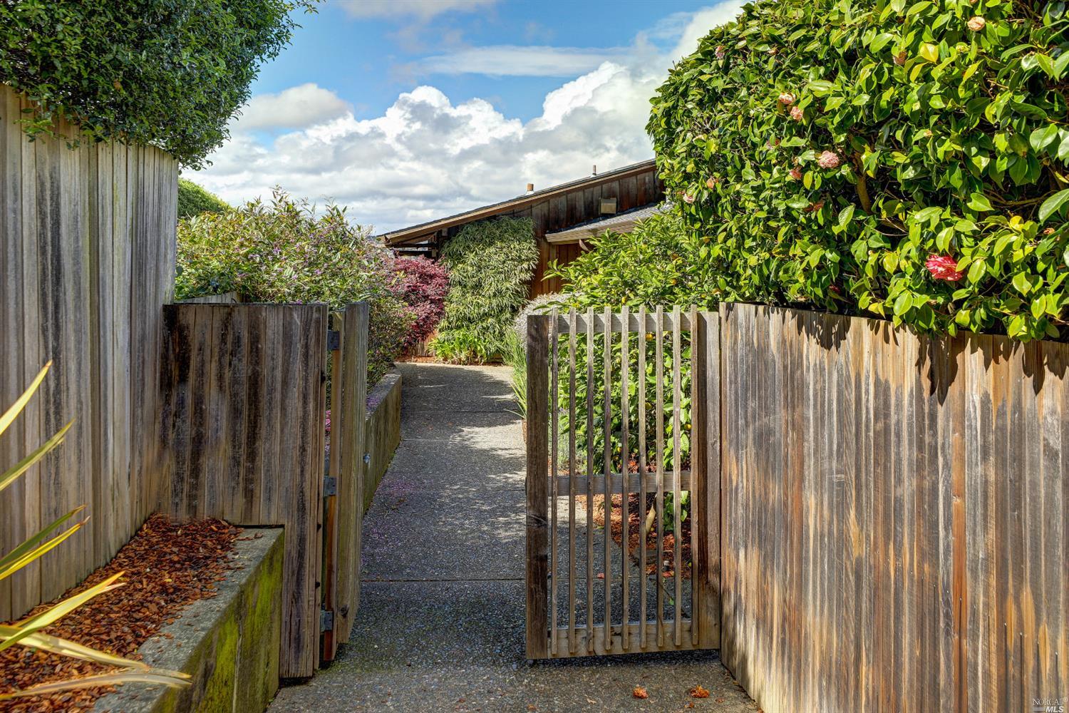 a view of a porch with potted plants and wooden fence