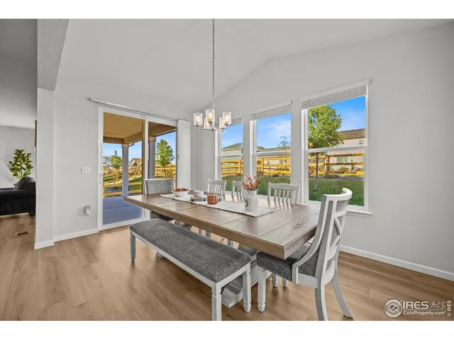 a dining room with wooden floor a chandelier a wooden table and chairs