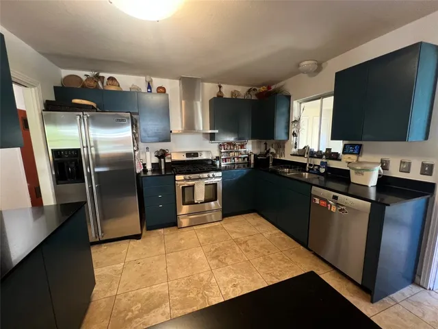 a kitchen with stainless steel appliances granite countertop a sink a stove and a refrigerator