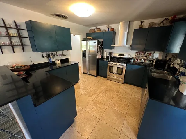 a kitchen with stainless steel appliances kitchen island granite countertop a refrigerator stove and microwave