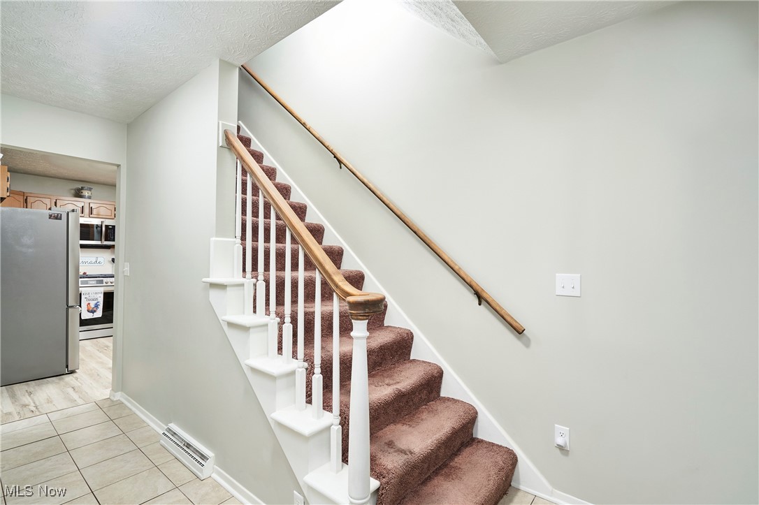 2835 Sunnybrook Road Mogadore, OH 44260 - Photo 2 of 27 Stairway featuring a textured ceiling, tile patterned floors, and a baseboard radiator