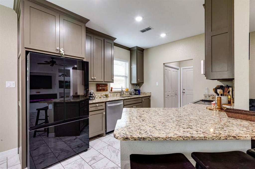 206 Willowbrook Avenue Tyler, TX 75702 - Photo 9 of 25 a kitchen with kitchen island granite countertop wooden cabinets and refrigerator