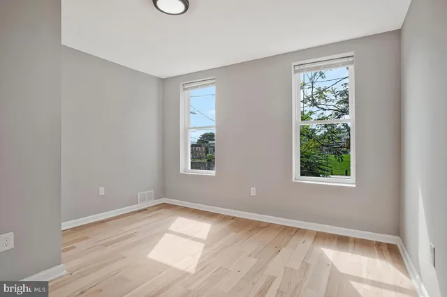 an empty room with wooden floor and windows