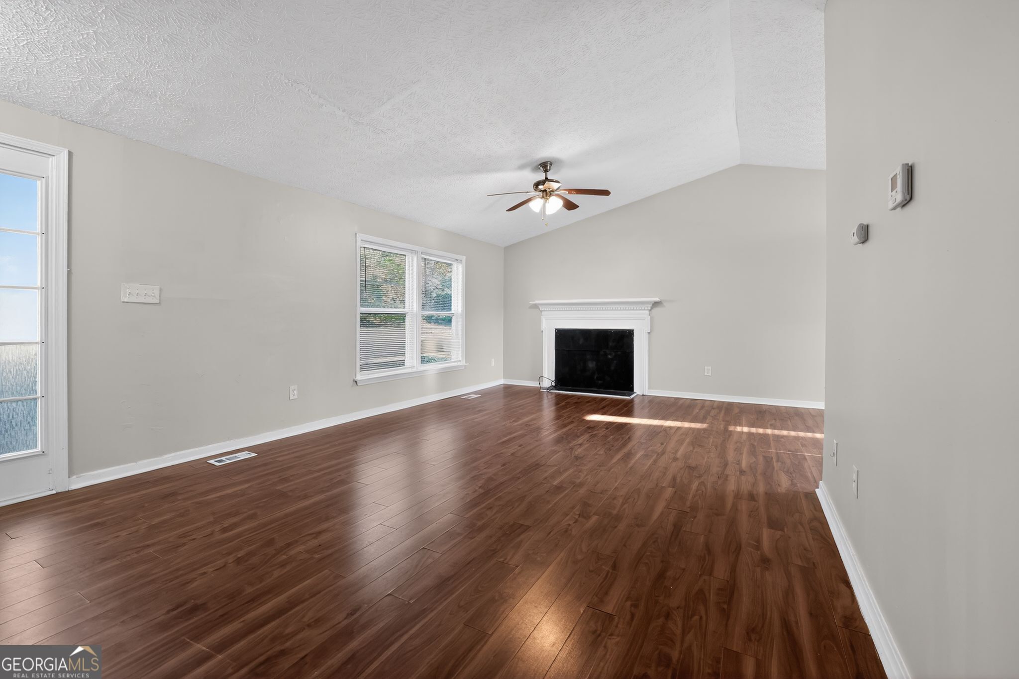 3798 Radcliffe Boulevard Decatur, GA 30034 - Photo 9 of 32 a view of an empty room with wooden floor fireplace and a window