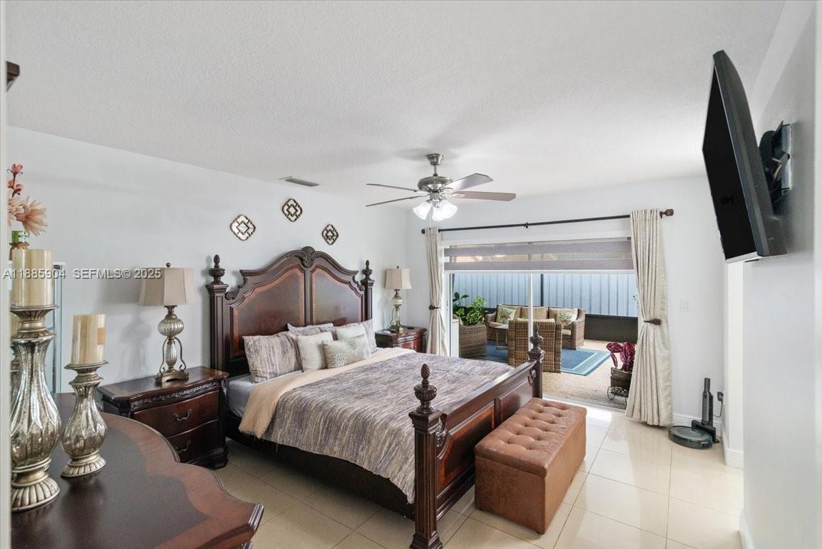14500 Southwest 173rd Street Miami, FL 33177 - Photo 28 of 47 a bedroom with a bed a couch and a flat tv screen on the dresser