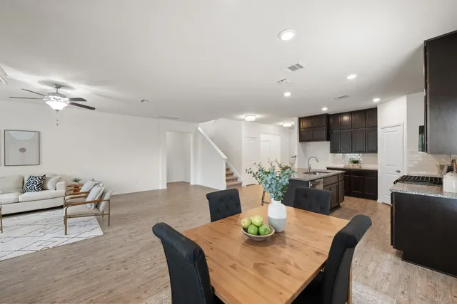 a living room with furniture kitchen view and a wooden floor
