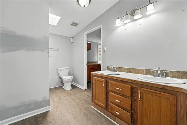 a spacious bathroom with a granite countertop sink a toilet and a mirror