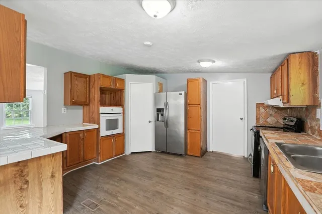 a kitchen with stainless steel appliances granite countertop a refrigerator and a stove top oven