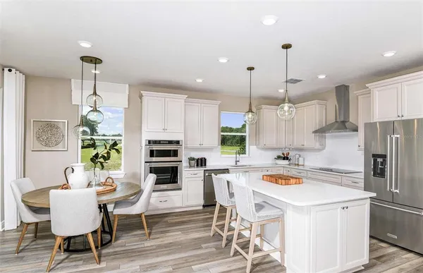 a kitchen with a dining table chairs appliances and cabinets