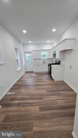 a view of a kitchen with kitchen island a sink wooden floor and a counter top space