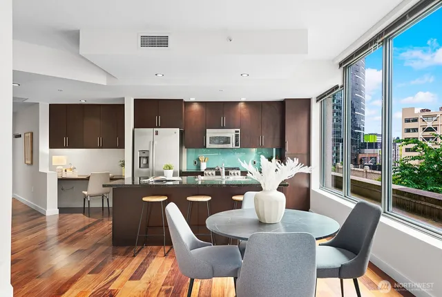 a dining room with furniture a wooden floor and a kitchen view