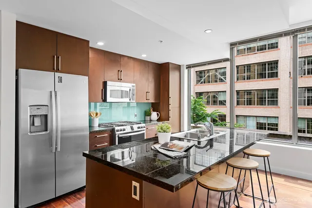 a kitchen with stainless steel appliances granite countertop a table chairs and a refrigerator