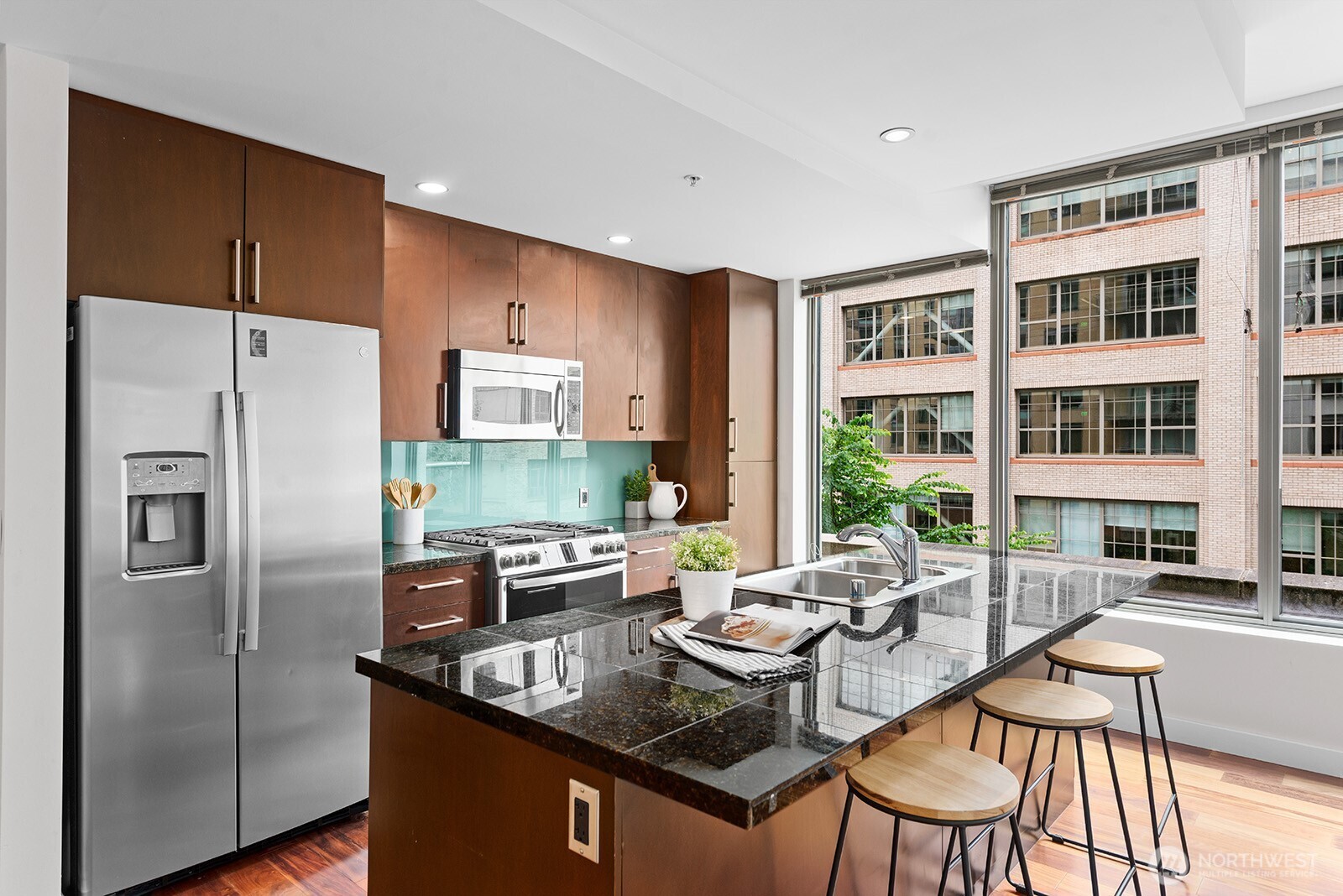 910 Lenora Street, Unit S403 Seattle, WA 98121 - Photo 6 of 40 a kitchen with stainless steel appliances granite countertop a table chairs and a refrigerator