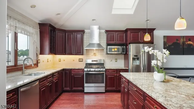 a kitchen with stainless steel appliances granite countertop a sink a stove and a wooden cabinets
