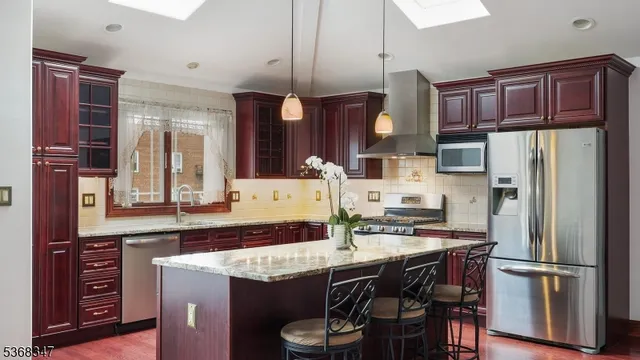 a kitchen with stainless steel appliances granite countertop a refrigerator a stove top oven a sink and cabinets