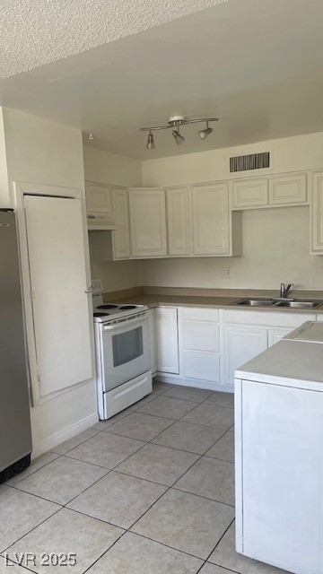 350 East Desert Inn Road, Unit B103 Las Vegas, NV 89109 - Photo 16 of 25 Kitchen featuring light tile patterned floors, electric stove, white cabinetry, stainless steel fridge, and under cabinet range hood