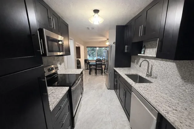 a kitchen with granite countertop stainless steel appliances a sink stove top oven and cabinets