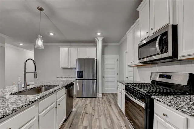 a kitchen with granite countertop a sink cabinets and wooden floor
